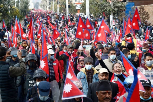 people are in streets, flag of Nepal is in their hand, and police is standing to control if the situation worsens